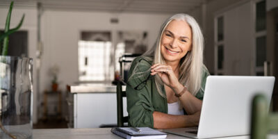 Mulher com autonomia no trabalho sorrindo sentada em frente a notebook