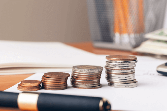 moedas e caneta em cima de folhas de papel representando o conceito de contabilidade
